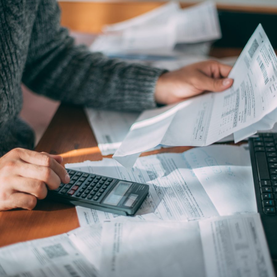 Close-up of male hands with a utility bill, a lot of checks and a calculator on the table. The man considers the costs of gas, electricity, heating. The concept of increasing tariffs for services